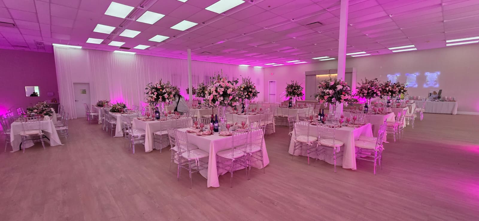 Full room overview with pink uplighting and clear chiavari chairs